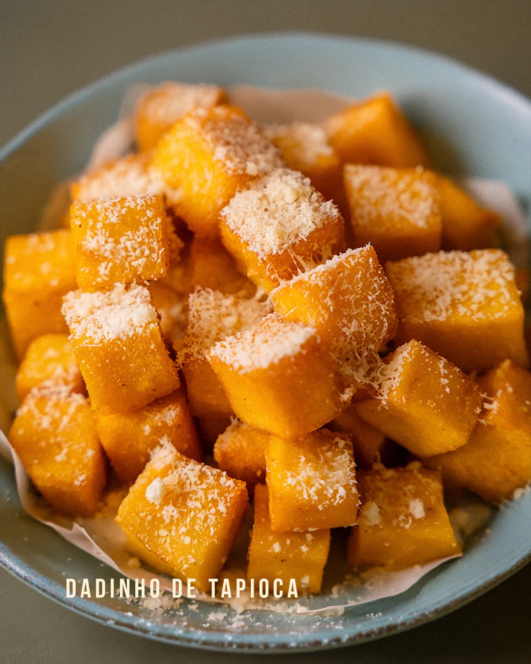 Dadinhos de tapioca com queijo ralado numa tigela azul