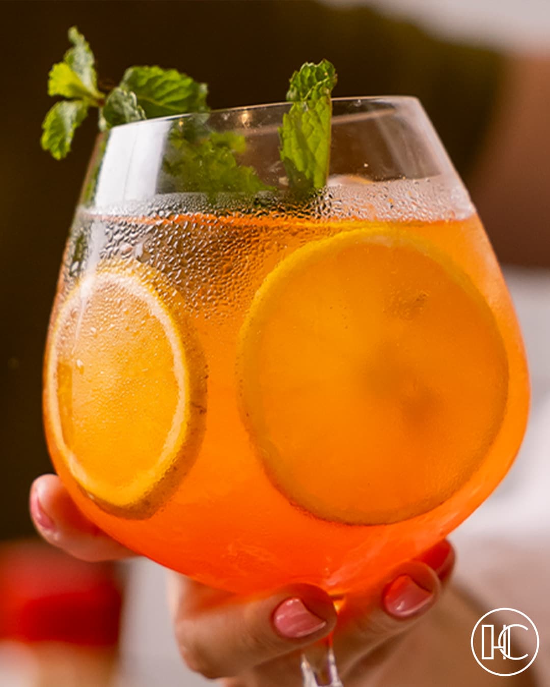 Drink laranja com rodelas de laranja e hortelã numa taça