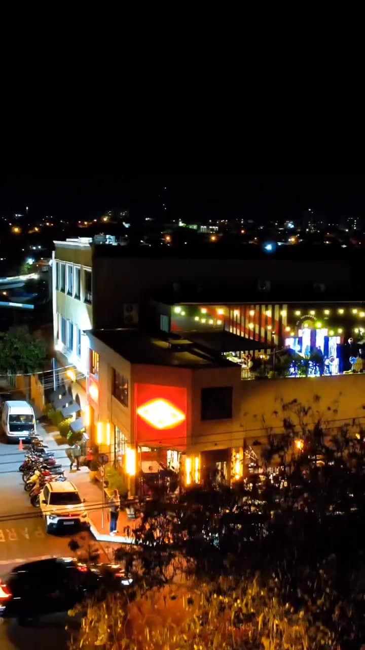 Vista do rooftop sobre a esquina, com o neon da fachada aceso embaixo